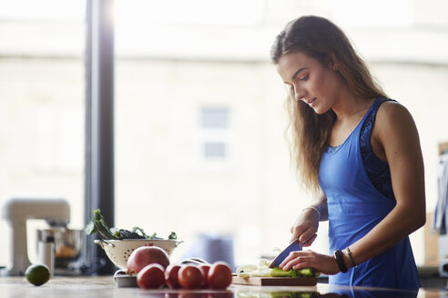 Junge Frau am Küchentisch beim Schneiden von Gemüse - CUF12526