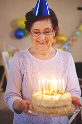 Ältere Frau mit Geburtstagstorte auf Party - CUF12581