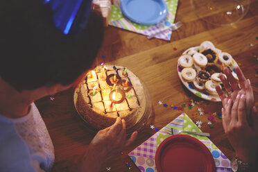 Senior woman looking at birthday cake at party - CUF12586