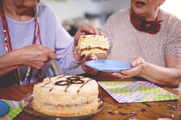 Ältere Frauen servieren Geburtstagskuchen auf einer Party - CUF12591