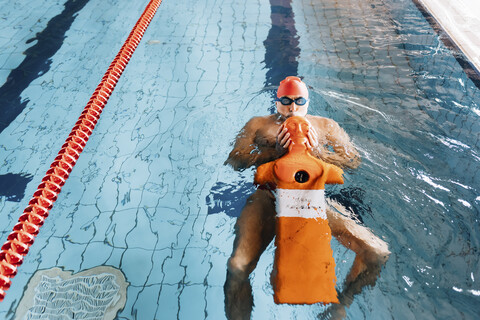 Älterer Mann bei der Vorbereitung einer Rettungsausrüstung im Schwimmbad, lizenzfreies Stockfoto