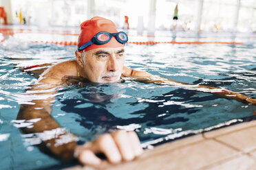 Älterer Mann entspannt sich im Wasser am Rande eines Swimmingpools - CUF12613