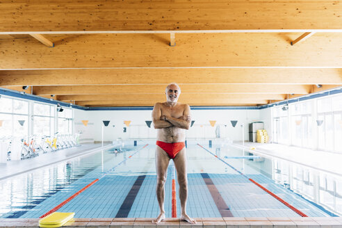 Senior man standing by swimming pool - CUF12619