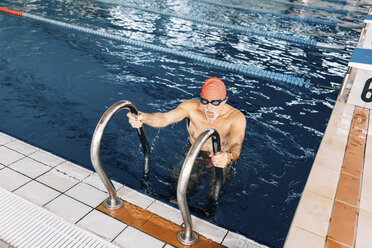 Senior man using ladder in swimming pool - CUF12624