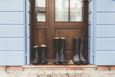Three pairs of rubber boots on doorstep - CUF12630