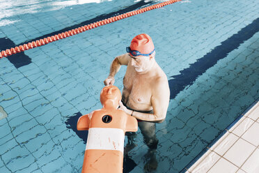 Älterer Mann bei der Vorbereitung einer Rettungsausrüstung im Schwimmbad - CUF12791
