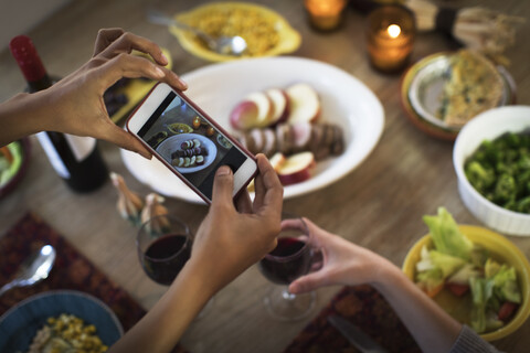 Hände von Freundinnen beim Fotografieren einer Mahlzeit am Küchentisch, lizenzfreies Stockfoto