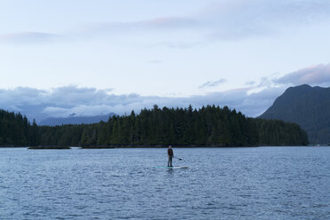 Mann steht auf einem Paddelbrett auf dem Wasser, Pacific Rim National Park, Vancouver Island, Kanada - ISF02117