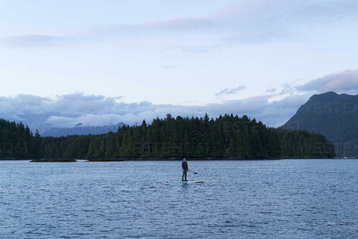 Man standing on paddle board on water, Pacific Rim National Park