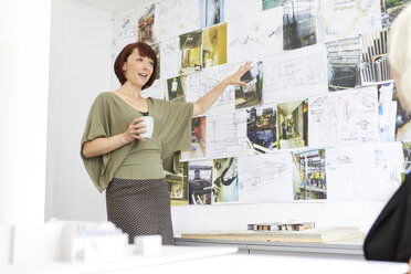 Architektin zeigt auf Moodboard in Büropräsentation - CUF12879