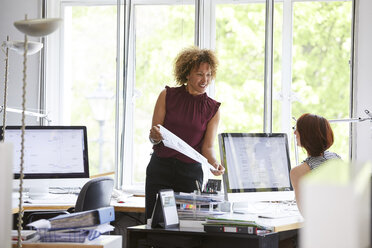 Female designers looking at blueprint in office - CUF12882