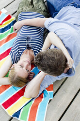 Blick von oben auf ein romantisches Paar, das auf einem Holzsteg sitzt - CUF12958