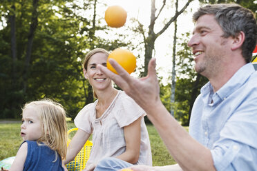 Älterer Mann jongliert Orangen beim Familienpicknick im Park - CUF12967