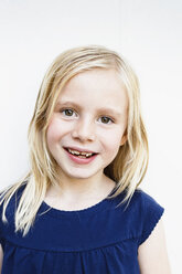 Portrait of cute girl with toothy grin in front of white wall - CUF12981