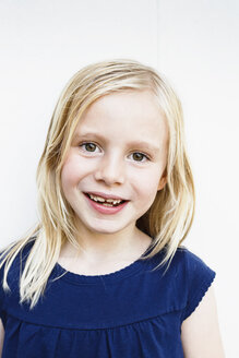 Porträt eines niedlichen Mädchens mit zahnigem Grinsen vor einer weißen Wand - CUF12981