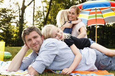 Junge Tochter liegt auf dem Vater beim Familienpicknick im Park - CUF12992