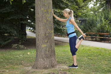 Ältere Frau streckt ihr Bein beim Training im Park - CUF13003