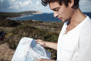 Ausgeschnittene Seitenansicht eines jungen Mannes, der auf eine Landkarte blickt, Castelsardo, Sardinien, Italien - CUF13033