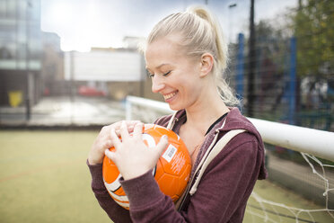 Young woman holding football, smiling - CUF13060