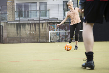 Junge Frau spielt Fußball auf einem städtischen Fußballplatz - CUF13061