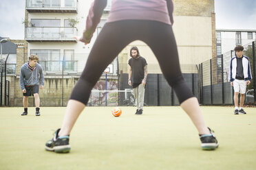 Group of adults playing football on urban football pitch - CUF13062