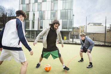 Eine Gruppe Erwachsener spielt Fußball auf einem städtischen Fußballplatz - CUF13071