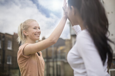 Two young women giving high five, outdoors - CUF13085