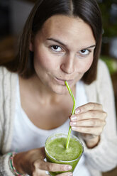 Frau trinkt grünen Smoothie mit Strohhalm - CUF13112