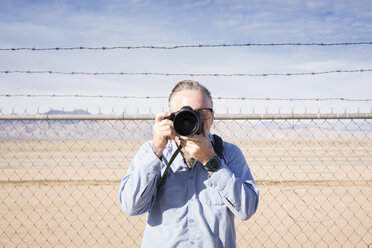 Fotograf vor einem Stacheldrahtzaun in der Wüste beim Fotografieren, Kalifornien, USA - ISF02150