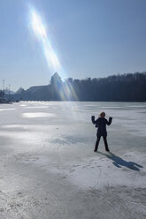 Girl standing on frozen lake, sun beam - HAMF00321