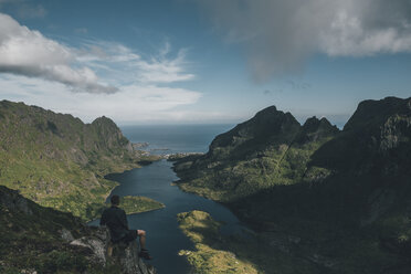 Norwegen , Lofoten, Reisender auf einem Felsen sitzend, Blick über den See Agvatnet - GUSF00758