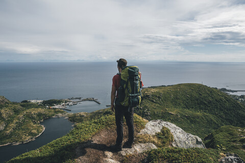 Norwegen,, Lofoten, Moskenesoy, Rucksacktourist auf Klippe stehend, Blick auf den Atlantik, lizenzfreies Stockfoto