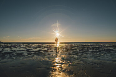 Norway, Lofoten, Moskenesoy, Man walking into the sunset at Kvalvika Beach - GUSF00771