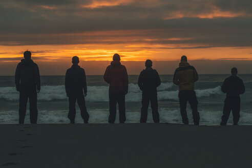 Norwegen, Lofoten, Moskenesoy, Junge Männer stehen am Bunes Strand bei Sonnenuntergang - GUSF00777