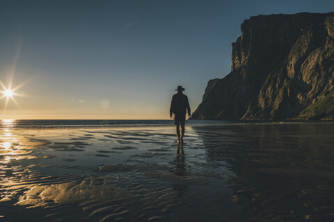 Norwegen, Lofoten, Moskenesoy, Mann geht in den Sonnenuntergang am Kvalvika Strand, lizenzfreies Stockfoto