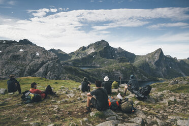 Norwegen, Lofoten, Moskenesoy, Junge Männer, die eine Pause machen und auf die Berge schauen - GUSF00806