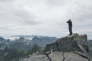 Norwegen, Lofoten, Moskenesoy, Junger Mann am Hermannsdalstinden stehend, Blick über den Kjerkefjord - GUSF00831