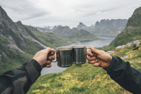 Norwegen, Lofoten, Moskenesoy, Zwei Personen, die mit Zinnbechern anstoßen - GUSF00832