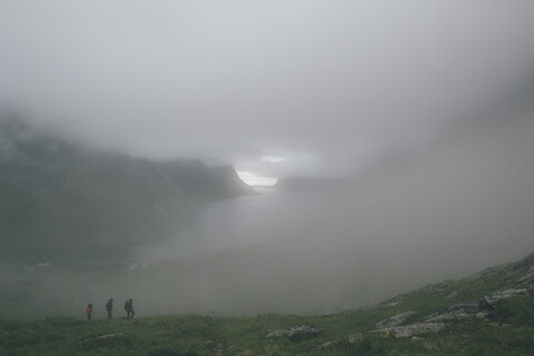 Norway, Lofoten, Moskenesoy, Three men hiking in the fog stock photo