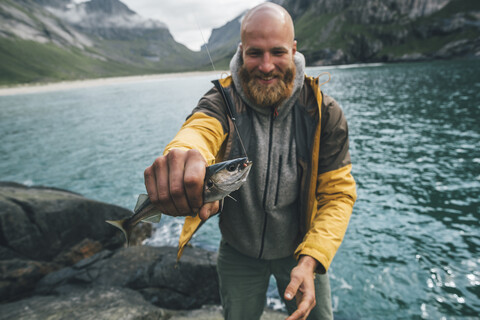 Norway, Lofoten, Moskenesoy, Young man holding freshly caught fish stock photo