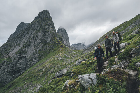 Norwegen, Lofoten, Moskenesoy, Junge Männer wandern auf dem Berg Markan, lizenzfreies Stockfoto