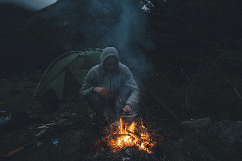 Norway, Lofoten, Moskenesoy, Young man sitting at camp fire stock photo