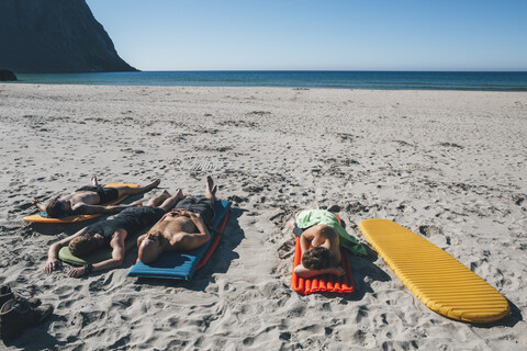 Norwegen, Lofoten, Moskenesoy, Freunde beim Sonnenbaden am Kvalvika Strand, lizenzfreies Stockfoto