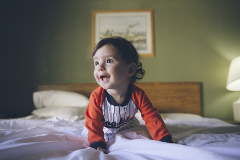 Porträt eines kleinen Mädchens, das einen Overall trägt und auf dem Bett krabbelt - GEMF01997