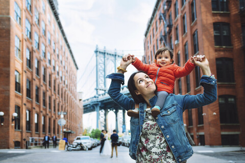 USA, New York, New York City, Mutter und Baby in Brooklyn mit der Manhattan Bridge im Hintergrund, lizenzfreies Stockfoto