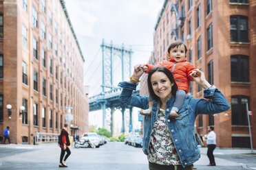 USA, New York, New York City, Mother and baby in Brooklyn with Manhattan Bridge in the background - GEMF02001
