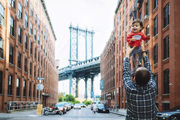 USA, New York, New York City, Vater spielt mit Baby in Brooklyn mit der Manhattan Bridge im Hintergrund - GEMF02002