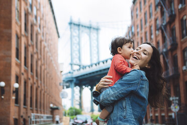 USA, New York, New York City, Baby kissing mother in Brooklyn with Manhattan Bridge in the background - GEMF02004