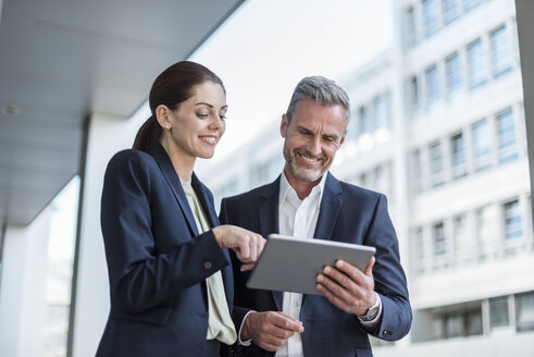 Portrait of two business partners looking together at tablet - DIGF04305