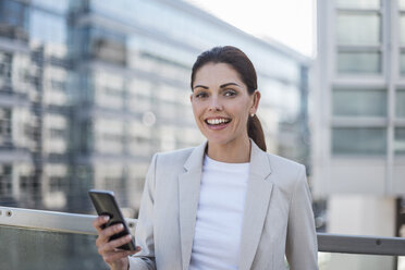 Portrait of smiling businesswoman with cell phone - DIGF04332